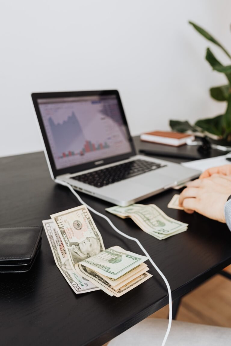 Bank notes and laptop on a desk — earning money online