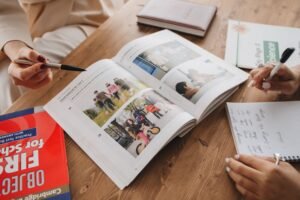 Hands taking notes while learning from an open book