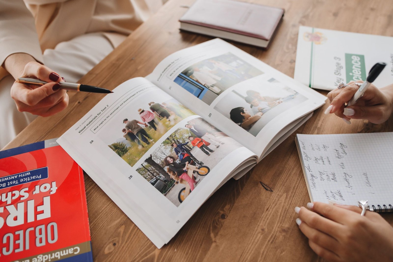 Hands taking notes while learning from an open book