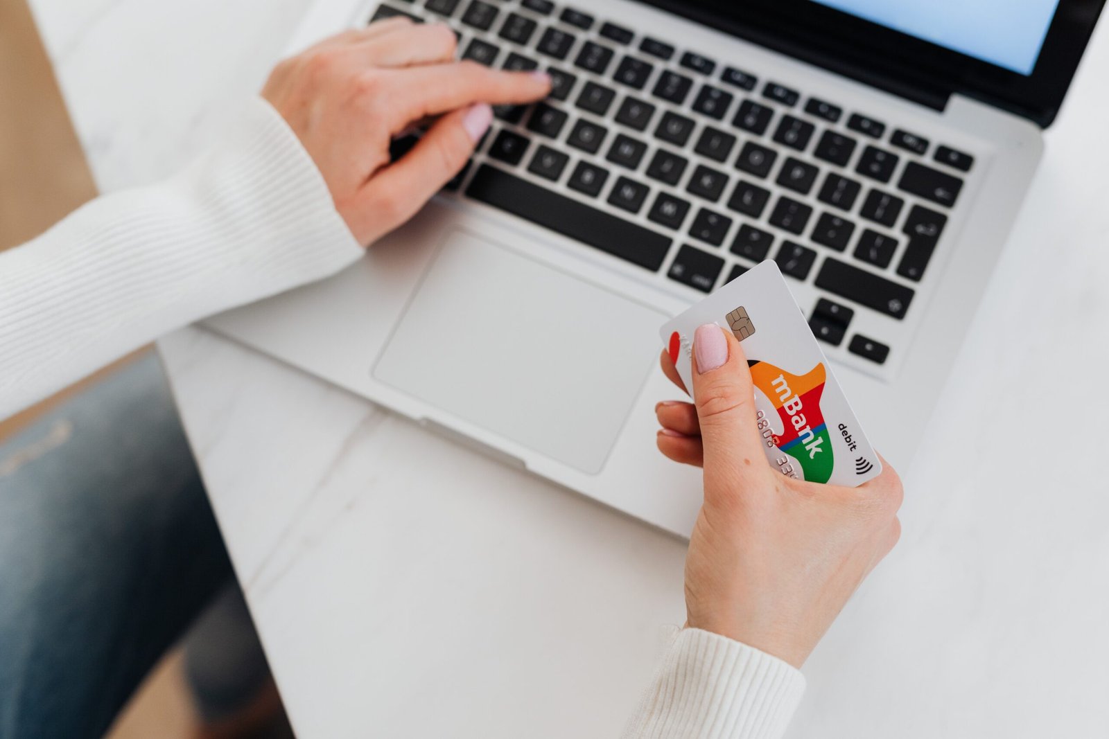 Person holding a bank card while shopping online on a laptop