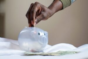 Hand putting a coin into a piggy bank — saving money concept