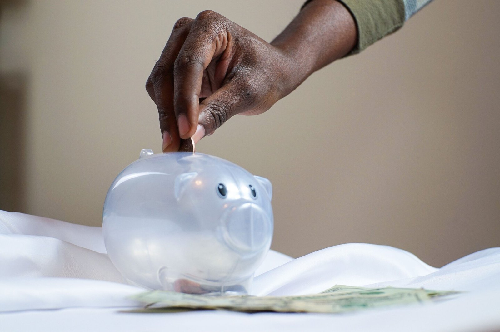 Hand putting a coin into a piggy bank — saving money concept